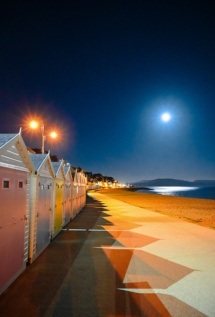 Lyme's iconic beach huts bathed in moonlight