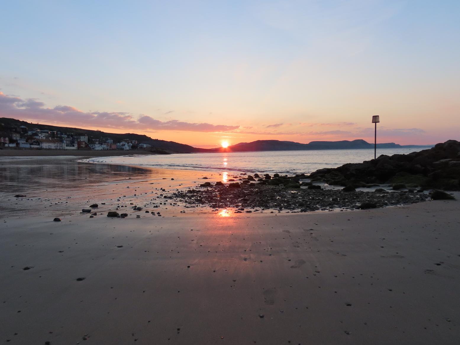 Sunrise viewed from sandy beach Lyme Regis
